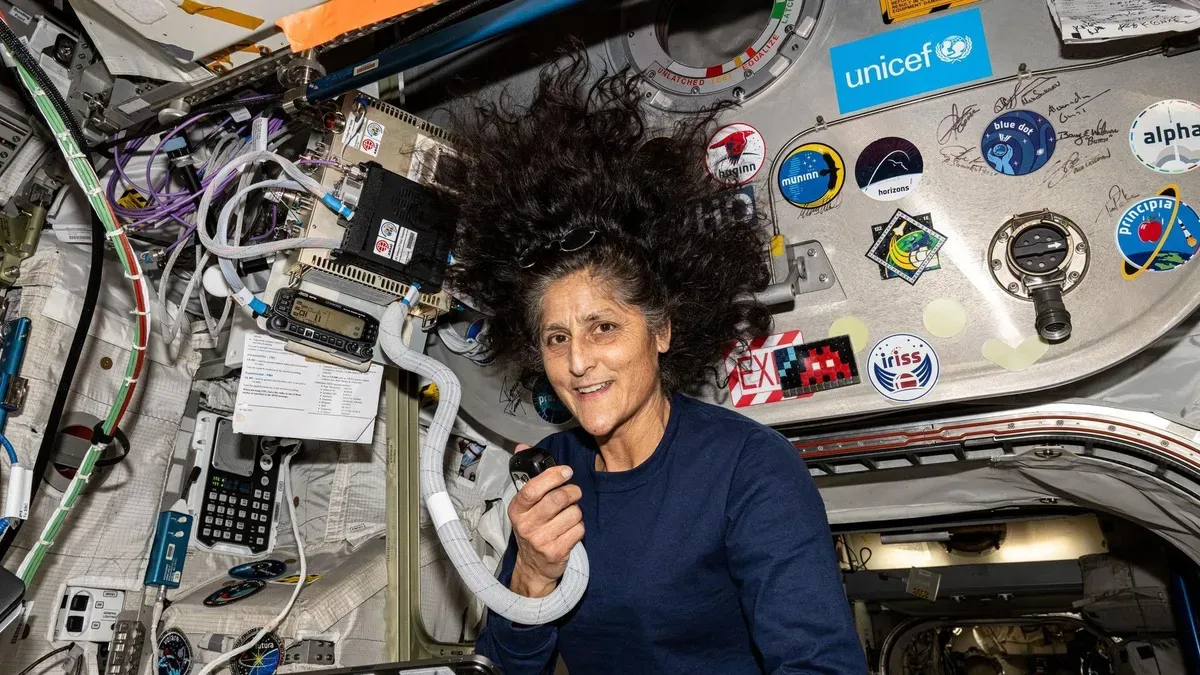 NASA astronaut Suni Williams during a spacewalk, wearing a red NASA emblem on her suit